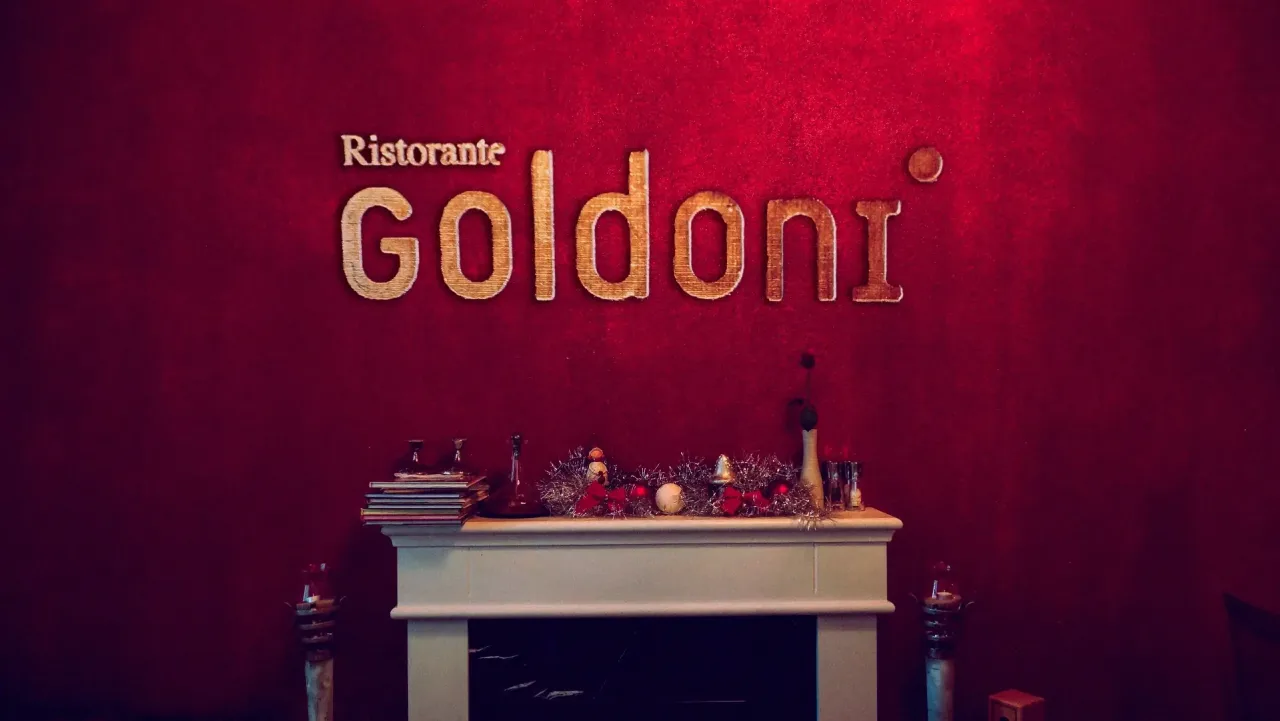 Ristorante Goldoni — Wandschild im Innenraum, gold auf rotem Samt